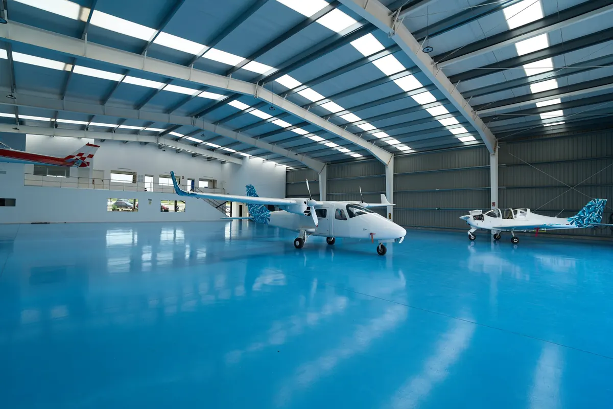 Aircraft hangar with a bright blue high-gloss epoxy floor and two small planes