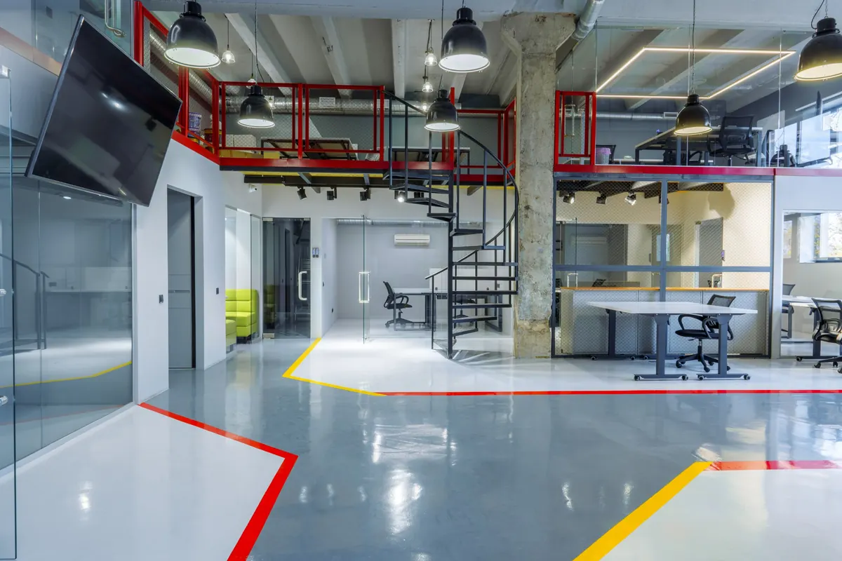 Modern office with gray epoxy flooring divided into zones with red and yellow floor lines